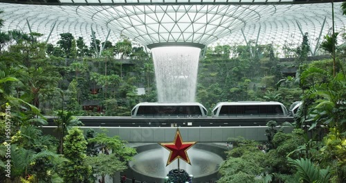 Airport train pass iconic rain vortex waterfall in Singapore rainforest; static photo