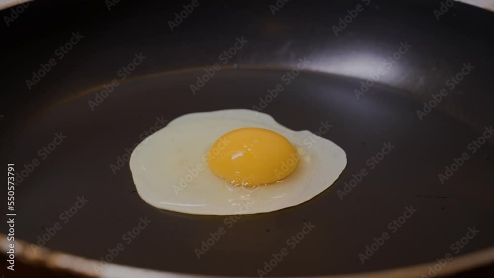 Close up egg dropping in frying pan and cooking. Close up egg falling into frying pan. Close up egg dropping in frying pan and cooking. Close up egg falling into frying pan.