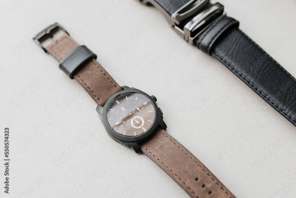 Presentation of detail brown casual hand watch and black formal belt with empty space for marketing material. Presentation of detail brown casual hand watch and black formal belt with empty space for marketing material.