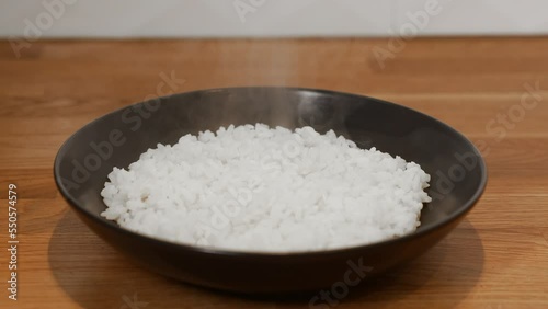 Hot steamed rice in the black plate. Steam and condensation appear above the hot rice. photo