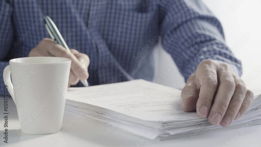 Hands of a workaholic sitting at his desk signing papers Hands of a workaholic sitting at his desk signing papers