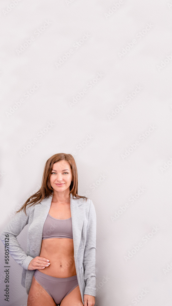 Happy young businesswoman wearing gray Underwear and jacket shows her perfect waist and sporty figure. Empty space for text Happy young businesswoman wearing gray Underwear and jacket shows her perfect waist and sporty figure. Empty space for text