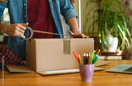 Man sealing parcel with duct tape. 