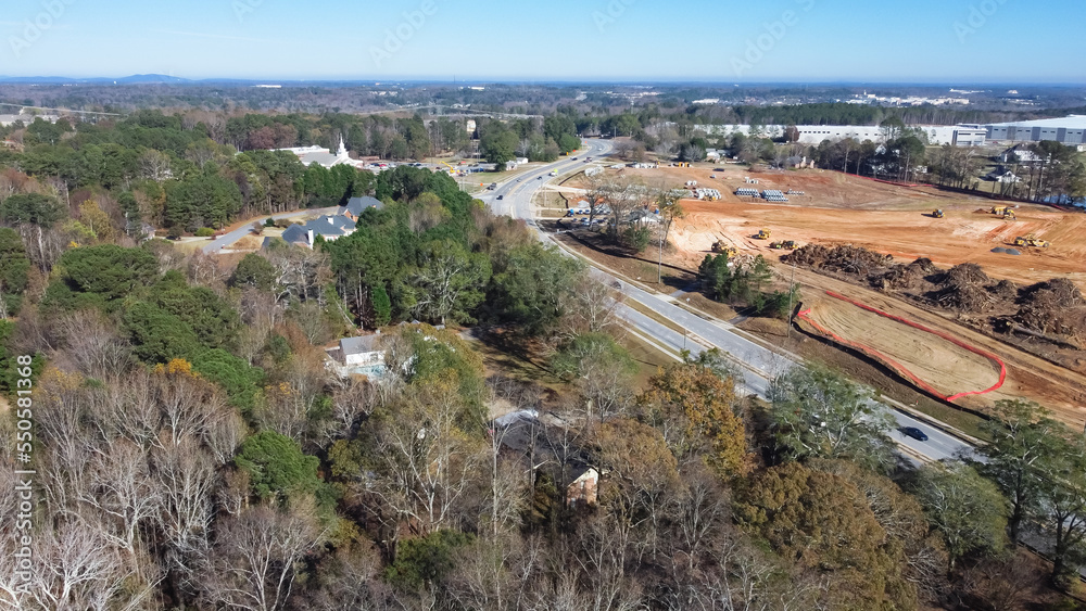 Residential neighborhood with small church near large construction project with raft foundation earthmoving work, heavy industrial machines at Camp Branch Rd in Buford, Georgia, US