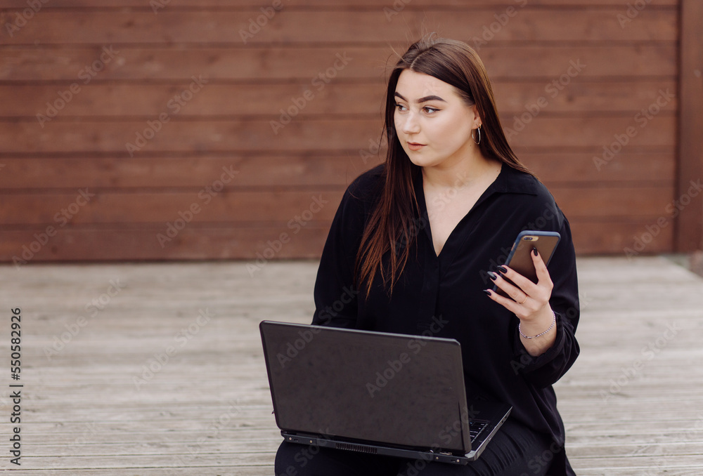 Young brown hair woman with laptop and smart phone computer sitting on wood floor Young brown hair woman with laptop and smart phone computer sitting on wood floor