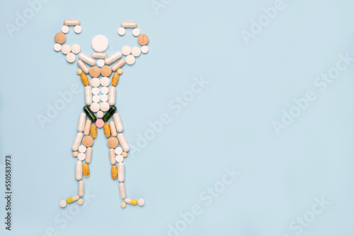 Shape of bodybuilder made of pills on blue background photo