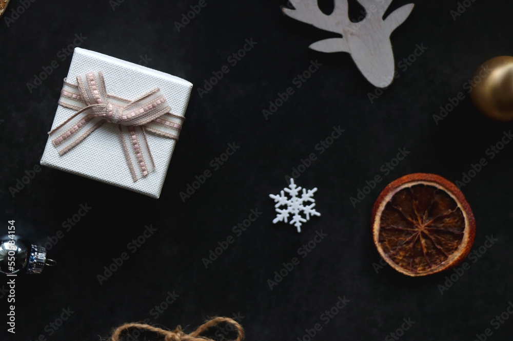 Small presents, various Christmas ornaments and deer figurine on dark background. Top view. Small presents, various Christmas ornaments and deer figurine on dark background. Top view.