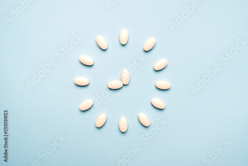 Time to take pills. Clock created from white pills on  blue background. Right time for using medicines