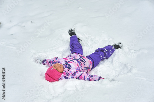 Obraz na płótnie Happy little girl rejoices in winter lying on the snow w salonie