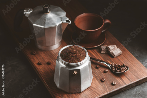 Moka coffee pot filled with brown ground coffee on dark wooden board, prepare to brewing Italian espresso photo