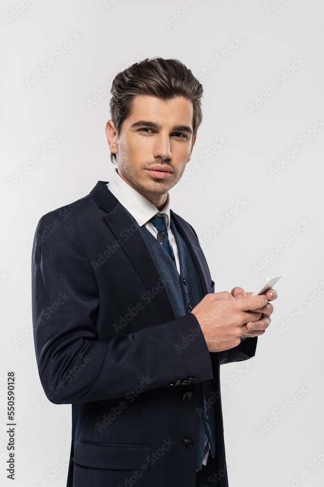 young and successful businessman in suit messaging on smartphone isolated on grey young and successful businessman in suit messaging on smartphone isolated on grey