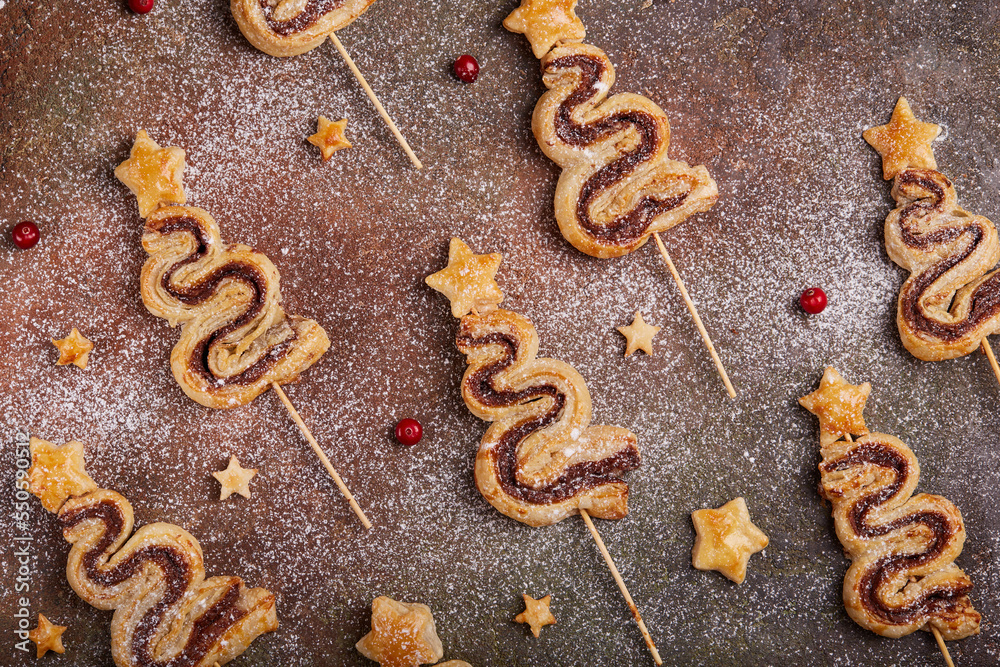 Christmas tree shape puff pastry cakes with chocolate filling and sugar powder. Delicious homemade New Year sweet baking. Christmas tree shape puff pastry cakes with chocolate filling and sugar powder. Delicious homemade New Year sweet baking.