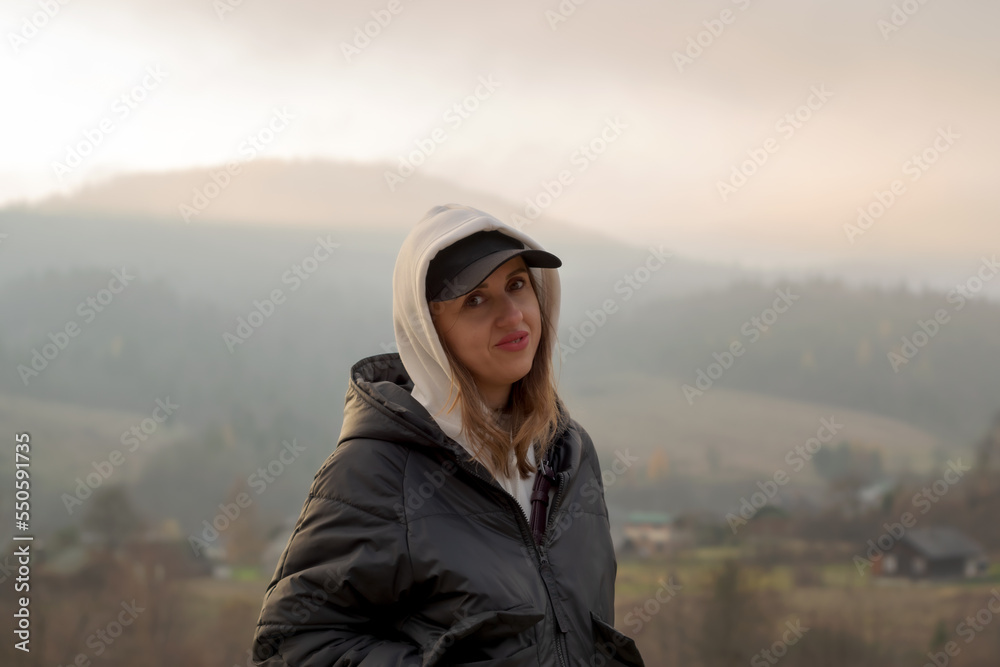 Portrait of a woman in a black jacket on a mountain background.