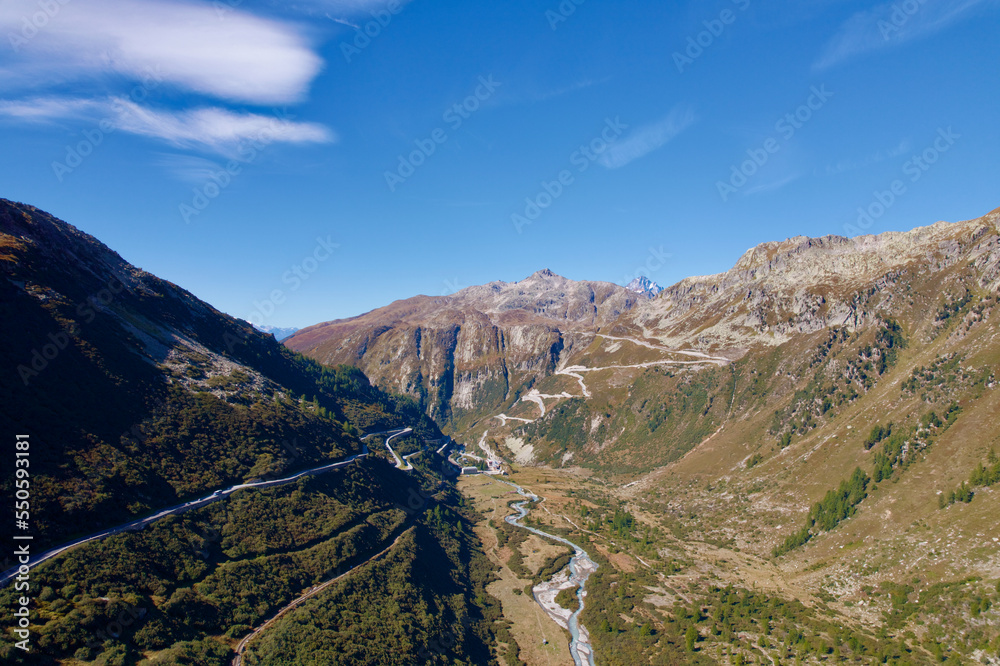 Mountain panorama with Rhone River in the Swiss Alps at region of mountain pass Furkapass with serpentine road of Grimselpass in the background. Photo taken September 12th, 2022, Goms, Switzerland.