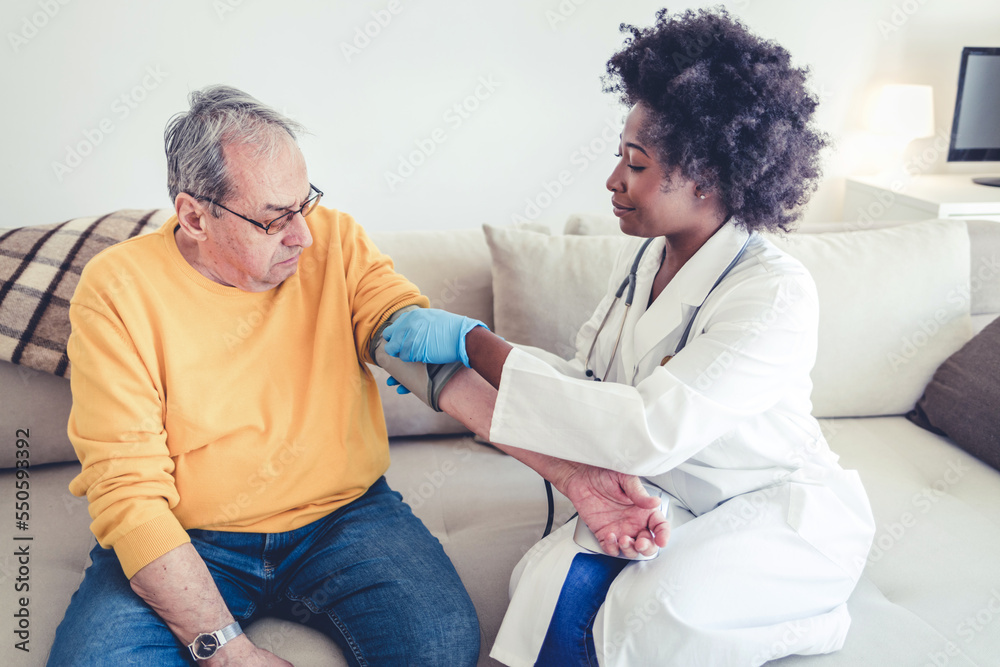 Obraz premium Elderly hypertension cardiovascular problems concept. Female nurse doing blood pressure measurement of a senior man patient. Doctor checking blood pressure of an elderly man at old age home.