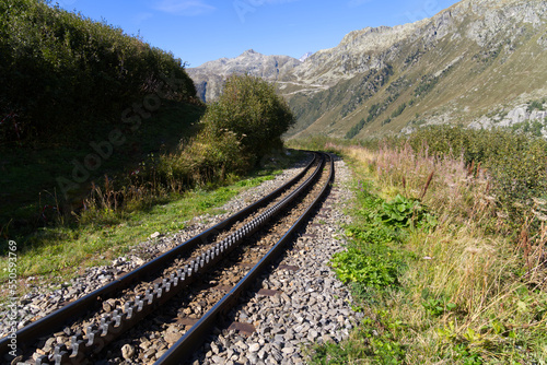 Cog wheel railway tracks of historic narrow gauge railway at Swiss mountain pass Furkapass on a sunny late summer day. Photo taken September 12th, 2022, Furka Pass, Switzerland.