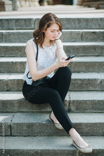 young girl with phone sitting on the stairs of an old house architecture