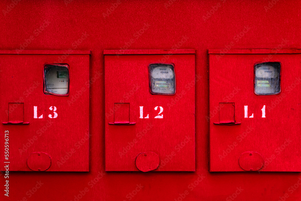 Red wall with with three numbered meter boxes.