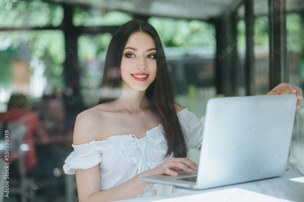 Portrait of beautiful smiling brunette woman sitting in a cafe with laptop outdoor. Portrait of beautiful smiling brunette woman sitting in a cafe with laptop outdoor.