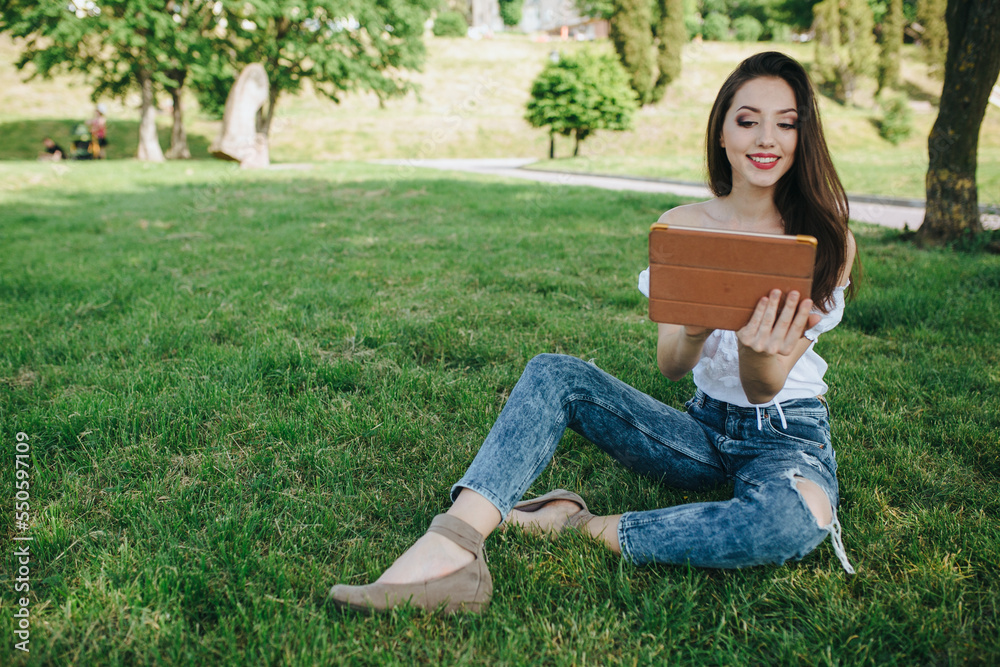 Young brunette woman, girl working with laptop, tablet and phone in green field, park with sunshine Young brunette woman, girl working with laptop, tablet and phone in green field, park with sunshine