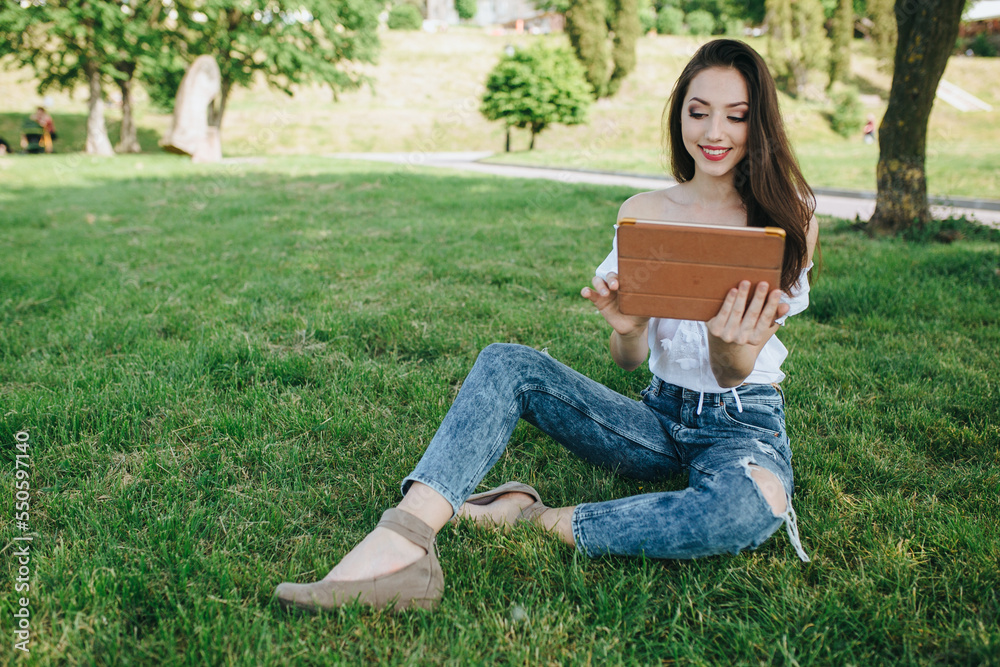 Young brunette woman, girl working with laptop, tablet and phone in green field, park with sunshine Young brunette woman, girl working with laptop, tablet and phone in green field, park with sunshine