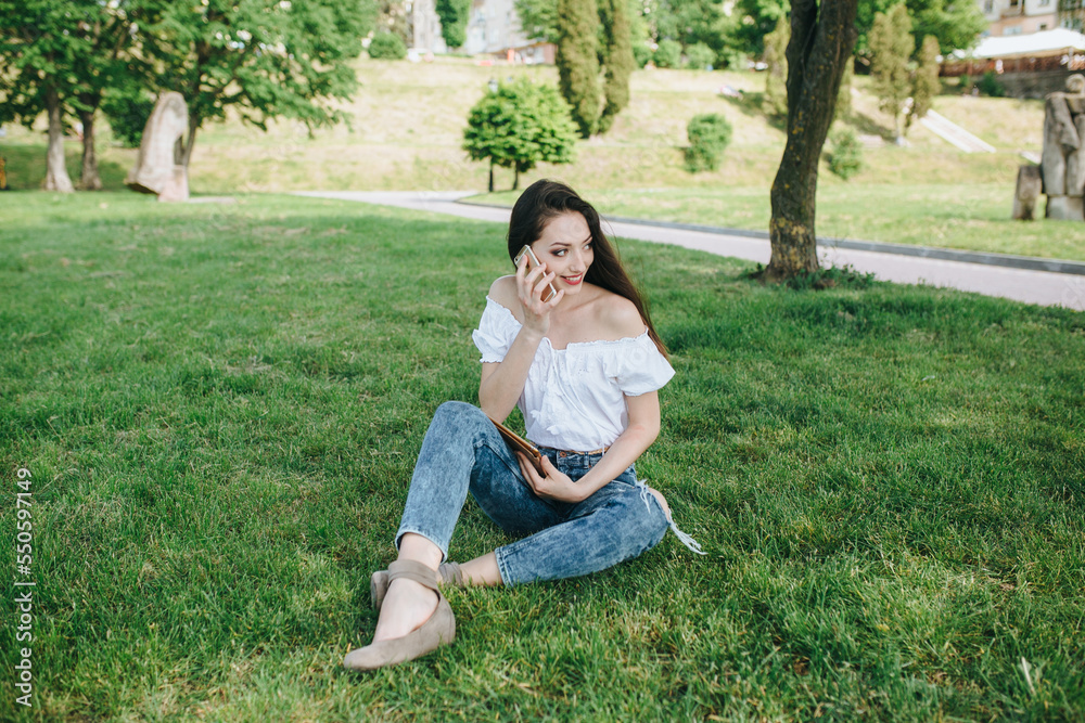 Young brunette woman, girl working with laptop, tablet and phone in green field, park with sunshine Young brunette woman, girl working with laptop, tablet and phone in green field, park with sunshine