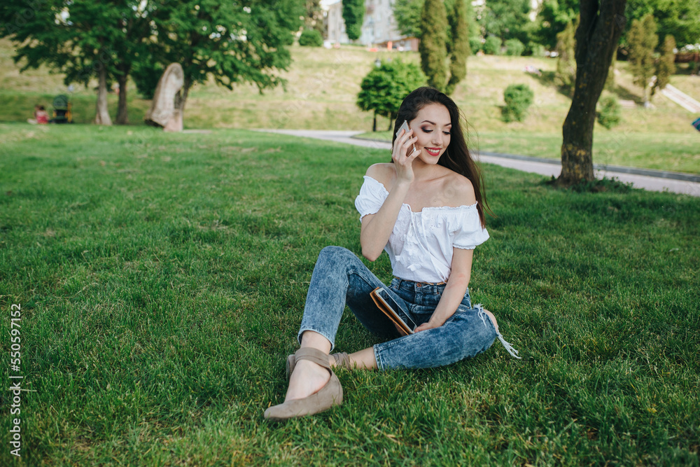 Young brunette woman, girl working with laptop, tablet and phone in green field, park with sunshine Young brunette woman, girl working with laptop, tablet and phone in green field, park with sunshine