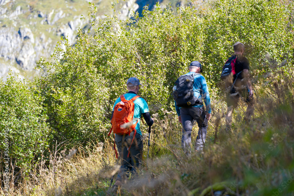 Men hiking group way up to Swiss mountain pass Furkapass on a sunny late summer day. Photo taken September 12th, 2022, Furka Pass, Switzerland.