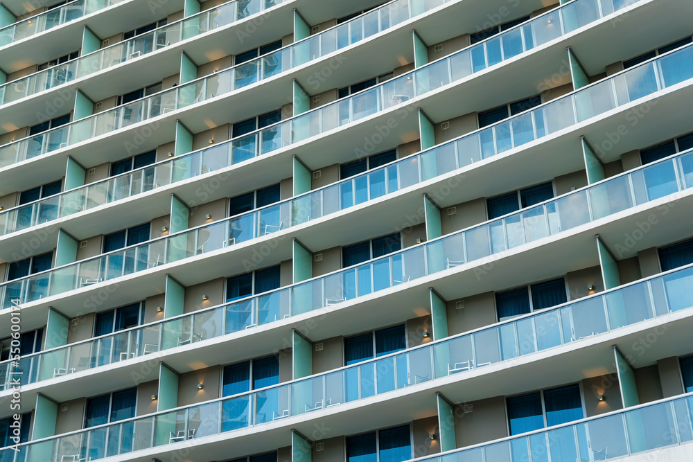 Close-up exterior of a condominium at Miami, FL with glass balcony railings and sliding glass doors Close-up exterior of a condominium at Miami, FL with glass balcony railings and sliding glass doors