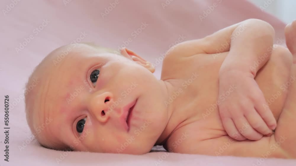 Portrait of a newborn baby. Caucasian child laying on the bed and looking around. Slow motion shot Portrait of a newborn baby. Caucasian child laying on the bed and looking around. Slow motion shot