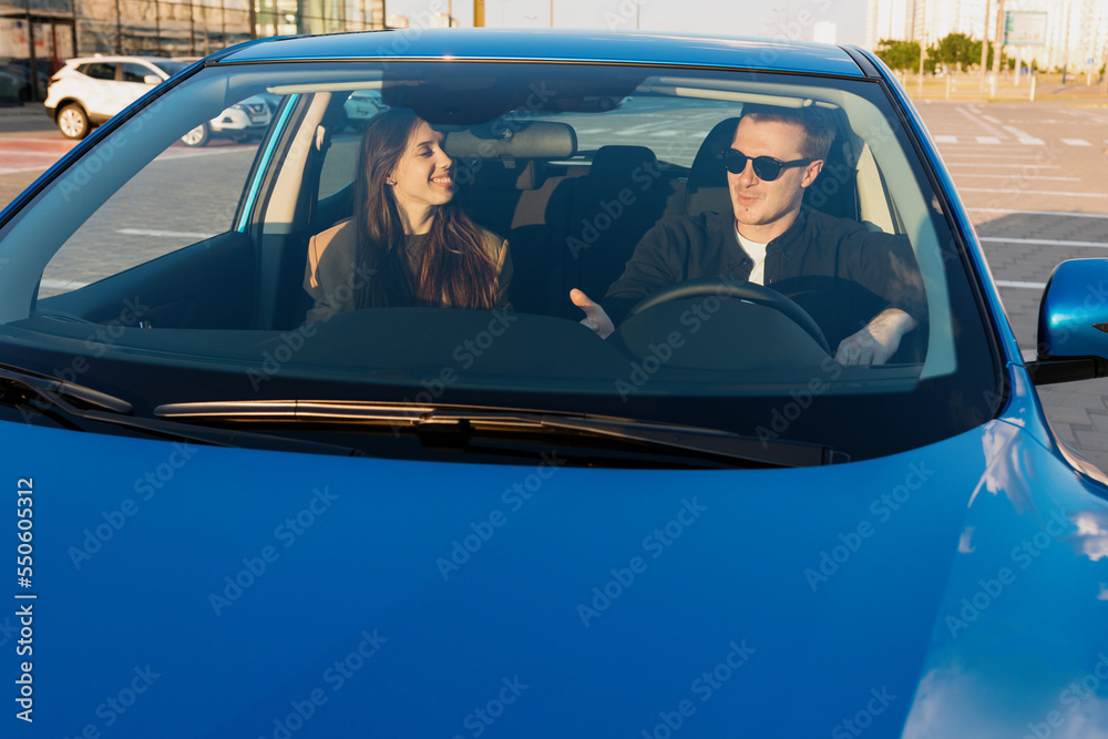 A young couple is sitting in a car in the parking lot. Test drive a new car before buying