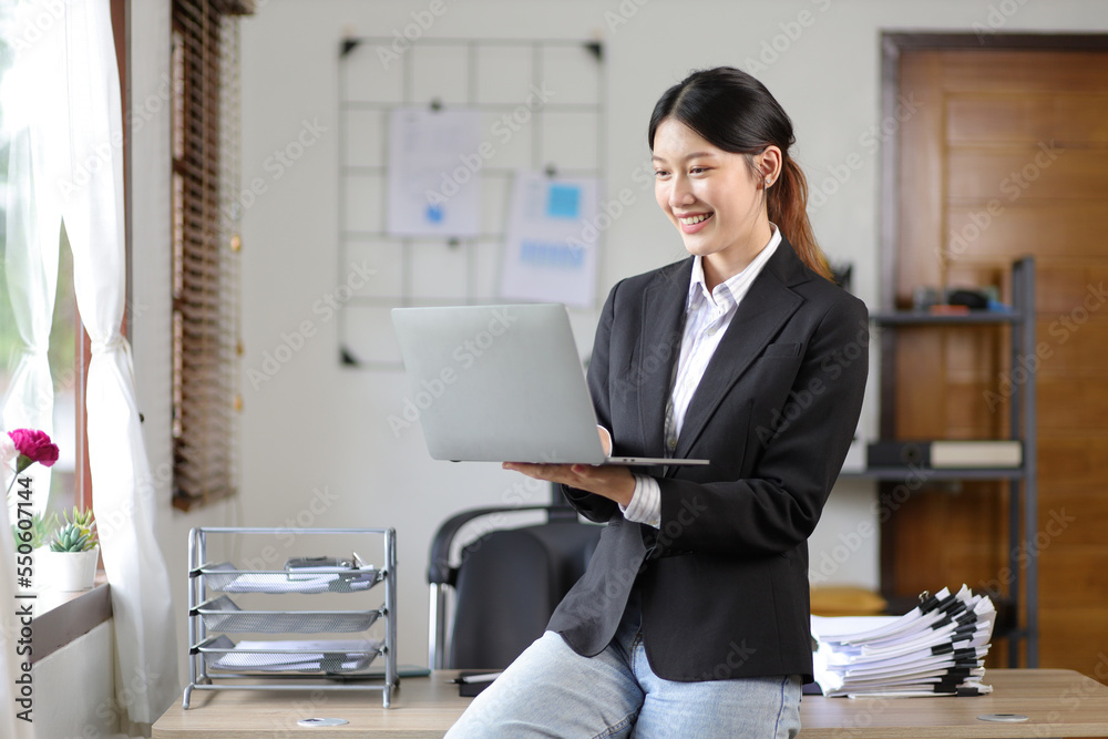 Portrait of a business woman standing working on a laptop in the office. Portrait of a business woman standing working on a laptop in the office.