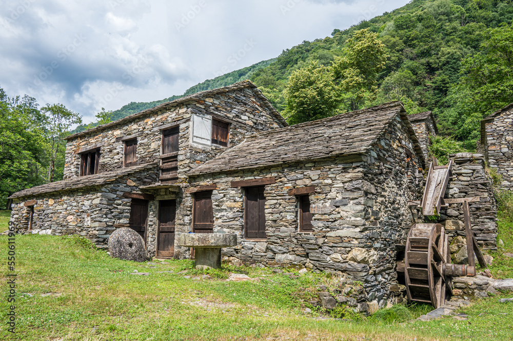 Obraz premium Stone watermill with wooden wheel in an abandoned mountain village in the Alps