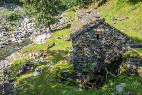 Stone watermill with wooden wheel in an abandoned mountain village in the Alps