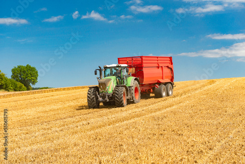 Tractor with loader wagon during grain harvest in the cornfield