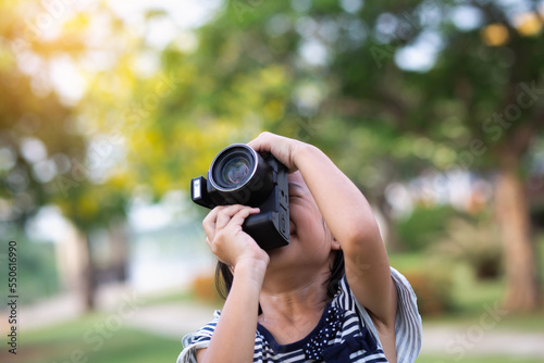 Asian little girl playing with toy camera in the park.