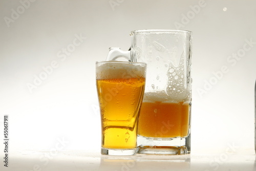 Foaming mug of beer in a glass against a white background