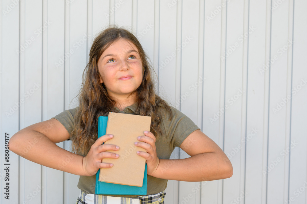 Smiling teen girl standing with notebooks against wall Smiling teen girl standing with notebooks against wall