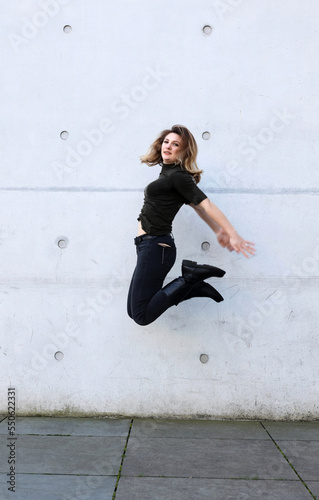 woman in black clothes jumping in front of grey wall