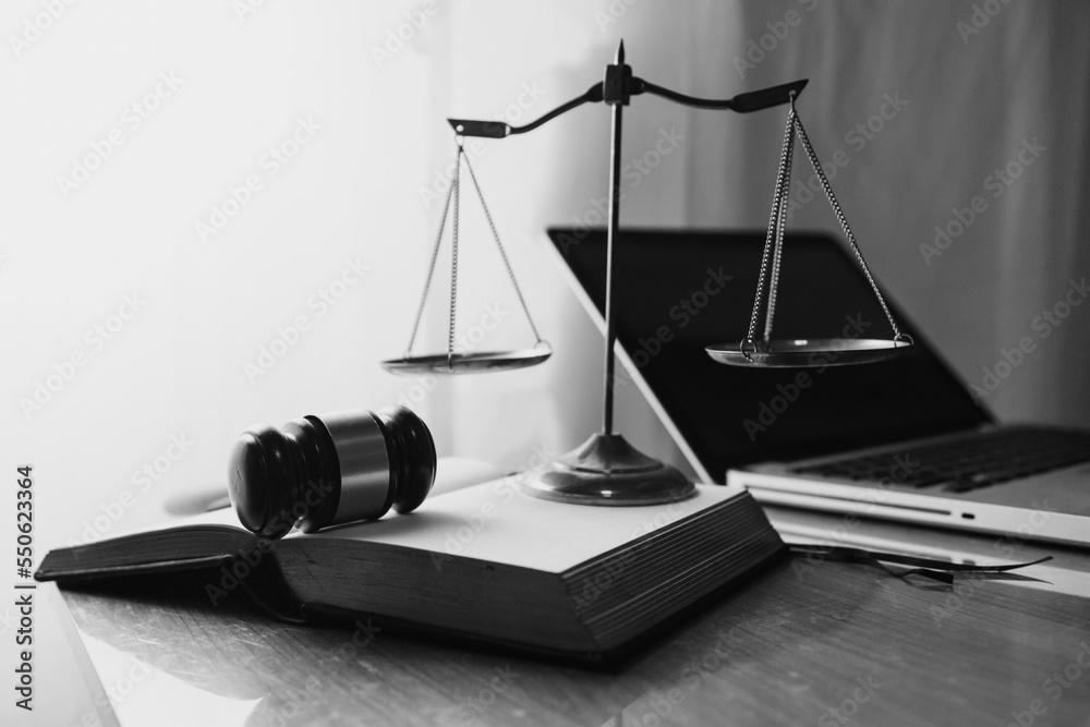 Justice and law concept.Male judge in a courtroom with the gavel, working with, computer and docking keyboard, eyeglasses, on table in morning light Justice and law concept.Male judge in a courtroom with the gavel, working with, computer and docking keyboard, eyeglasses, on table in morning light