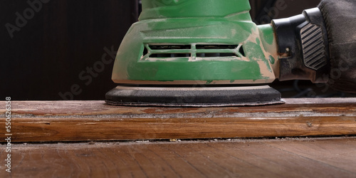 carpenter hand sanding a wooden door furniture with a grinder.