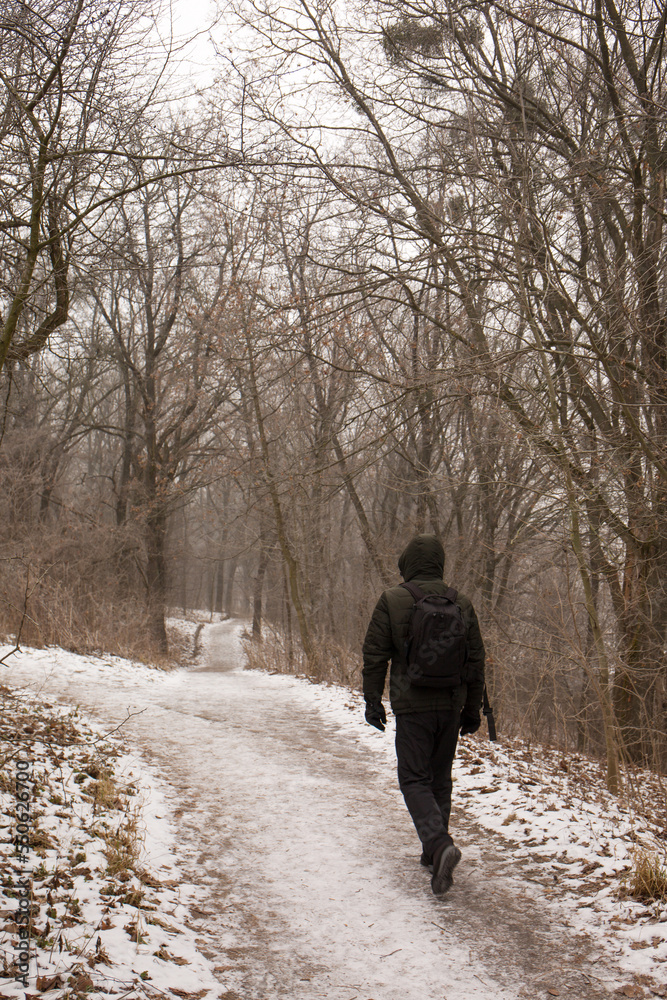 A man with a backpack walks in the park in winter