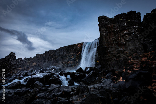 Oxararfoss waterfall  surrounded with black volcanic rocks in Thingvellir  Iceland. Dark  moody landscape. 