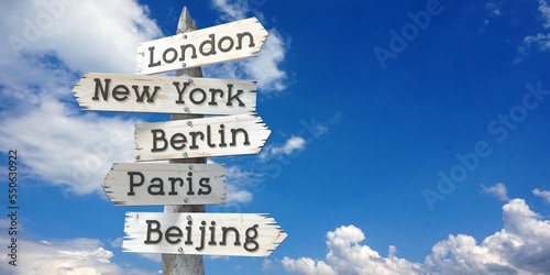 London, New York, Berlin, Paris, Beijing - wooden signpost with five arrows