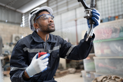 African American technician engineer man use walkie talkie with checking machine robot at factory 