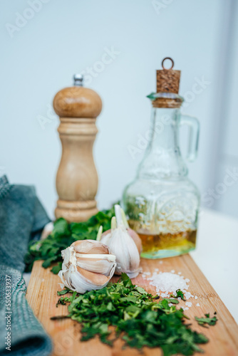 garlic, greens, salt on a wooden board, oil and a pepper mill. ingredients for health 