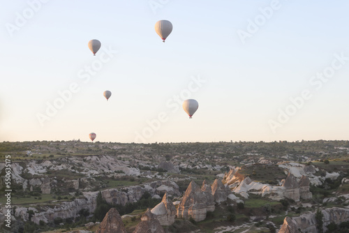 Hot air balloons fly in the evening sunset sky over Goreme National Park.