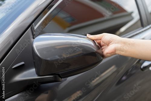 A woman closes a folding side mirror with her hands Folding side mirrors of a compact modern car.