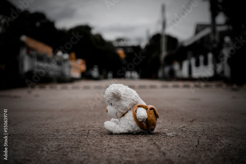 lonely teddy bear sleep on cement floor for created postcard  of international missing children, broken heart, lonely, sad, alone unwanted cute doll lost.