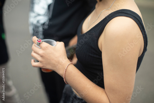 Girl hand. Summer clothes. Bare shoulder. Student holds something in her hand. Young skin of hand.